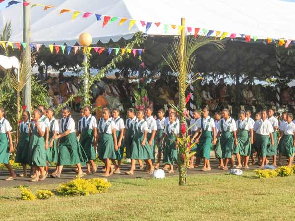 Inizia la sfilata per l'anniversario dell'indipendenza di Samoa. Ogni villaggio, ogni scuola, ogni oratorio, ogni organizzazione presenta una delegazione che sfila davanti al presidente, con canti e danze al suono dei tamburi. Tutti sono vestiti con i colori sociali del villaggio o del gruppo, le donne spesso hanno in testa ghirlande di fiori, e tutti rigorosamente indossano il lava-lava (uomini), il sarong (le donne) e calzano ai piedi gli infradito più belli che posseggono.